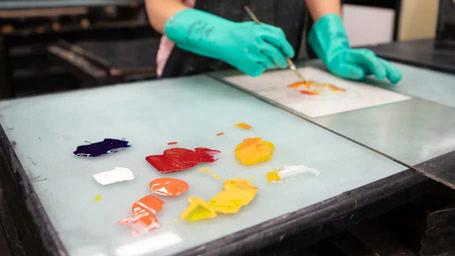 A student mixes printmaking ink in an intro class.