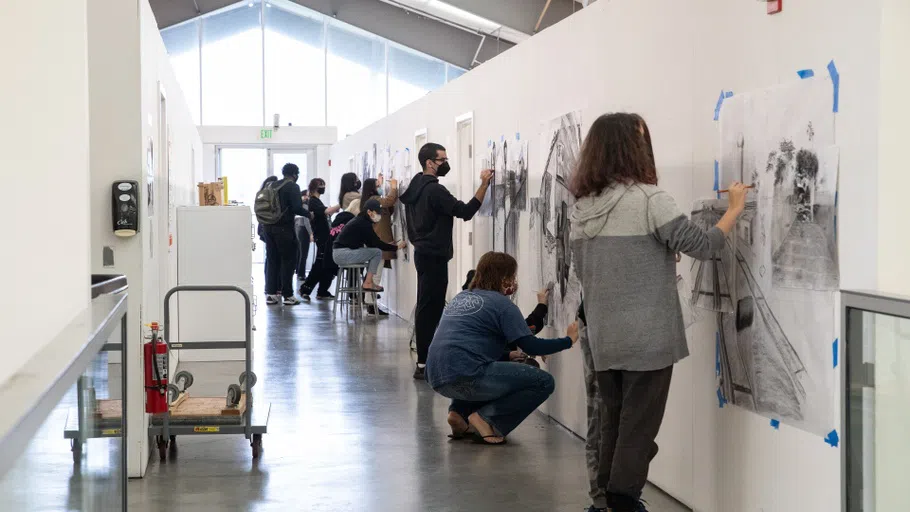 Students line a First Year hallway working on graphite drawings.