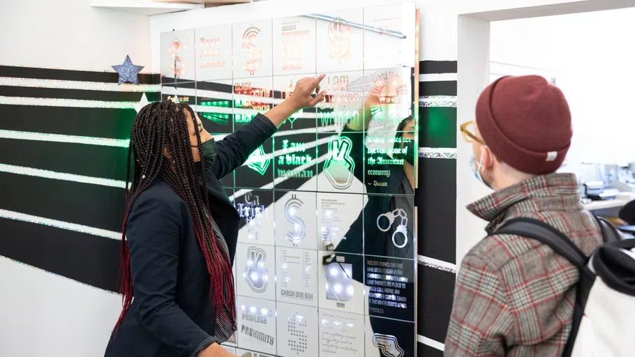 A student shows her mirrored installation to a faculty member.