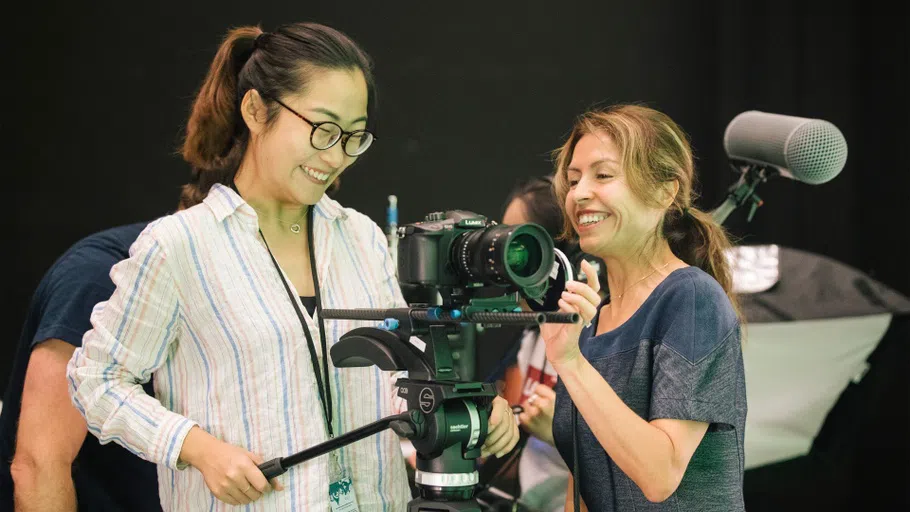 A student and faculty member smile while filming a panning shot.