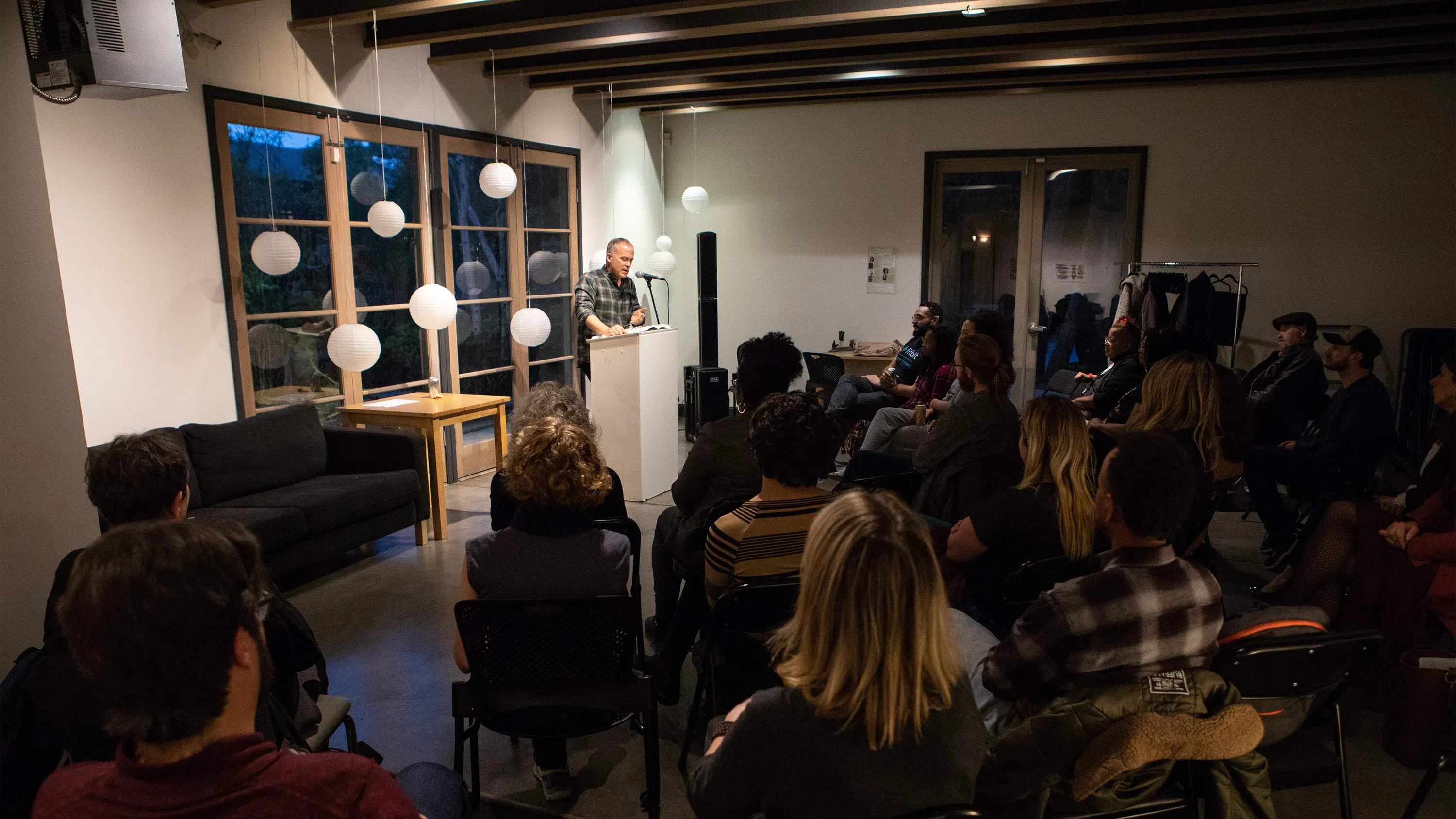 Professor Tom Barbash stands at a podium reading to an audience.