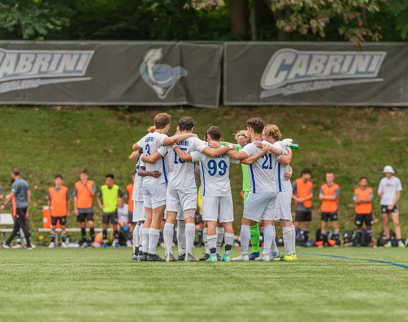 Men's soccer team huddles on the field before a game. 