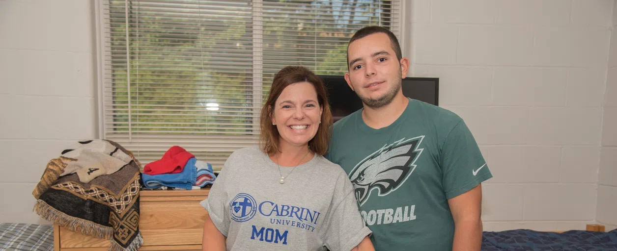 Mom smiling with her son in a Cabrini residence hall room. 