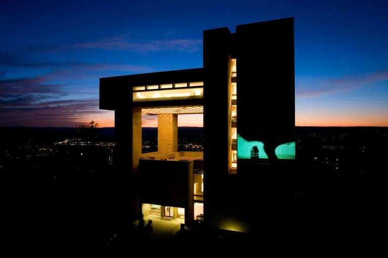 The Johnson Museum of Art lit up at dusk, with projection on the outside wall.