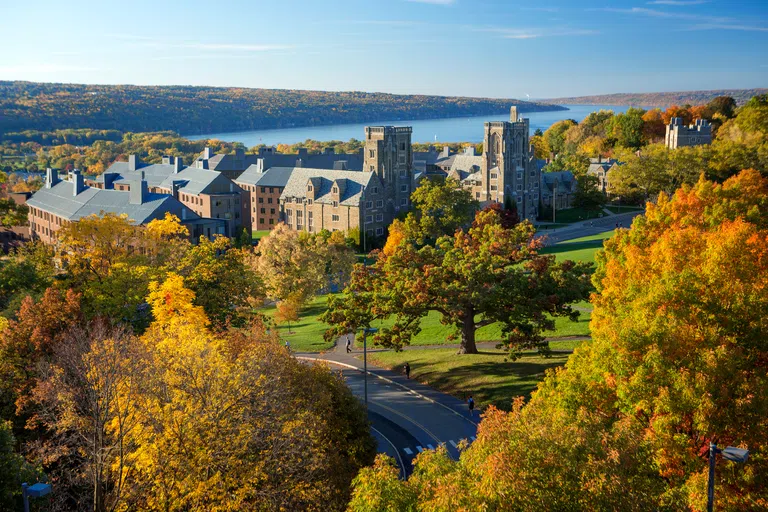 An aerial view of Libe Slope, with historic campus buildings and Cayuga Lake in the background.