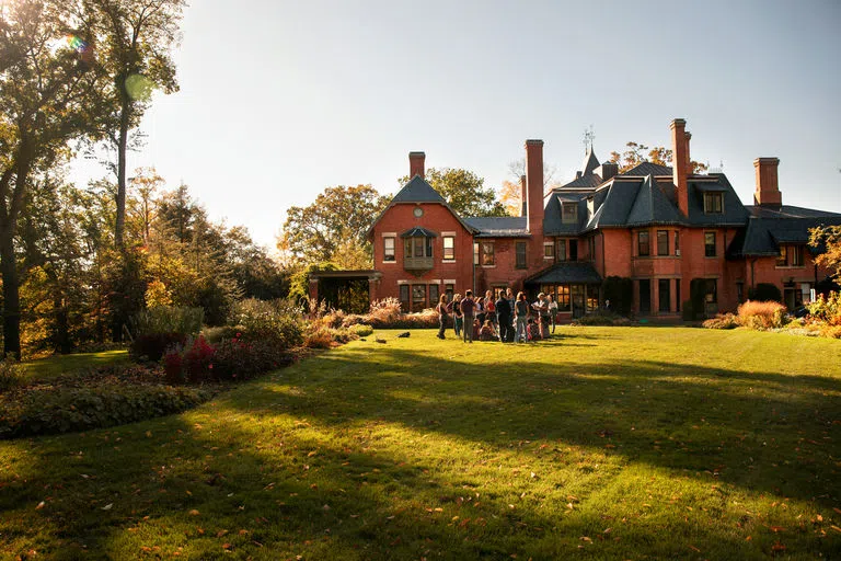 Students gather on the sunlit lawn in the garden behind the A.D. White House at Cornell. 