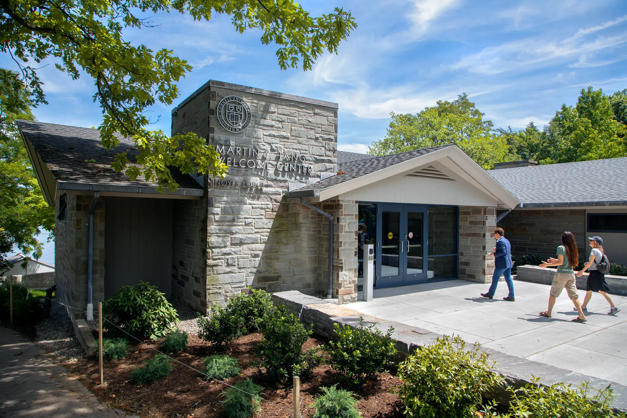 Exterior of the Martin Y. Tang Welcome Center. Photo is framed by a few tree branches and blue sky.