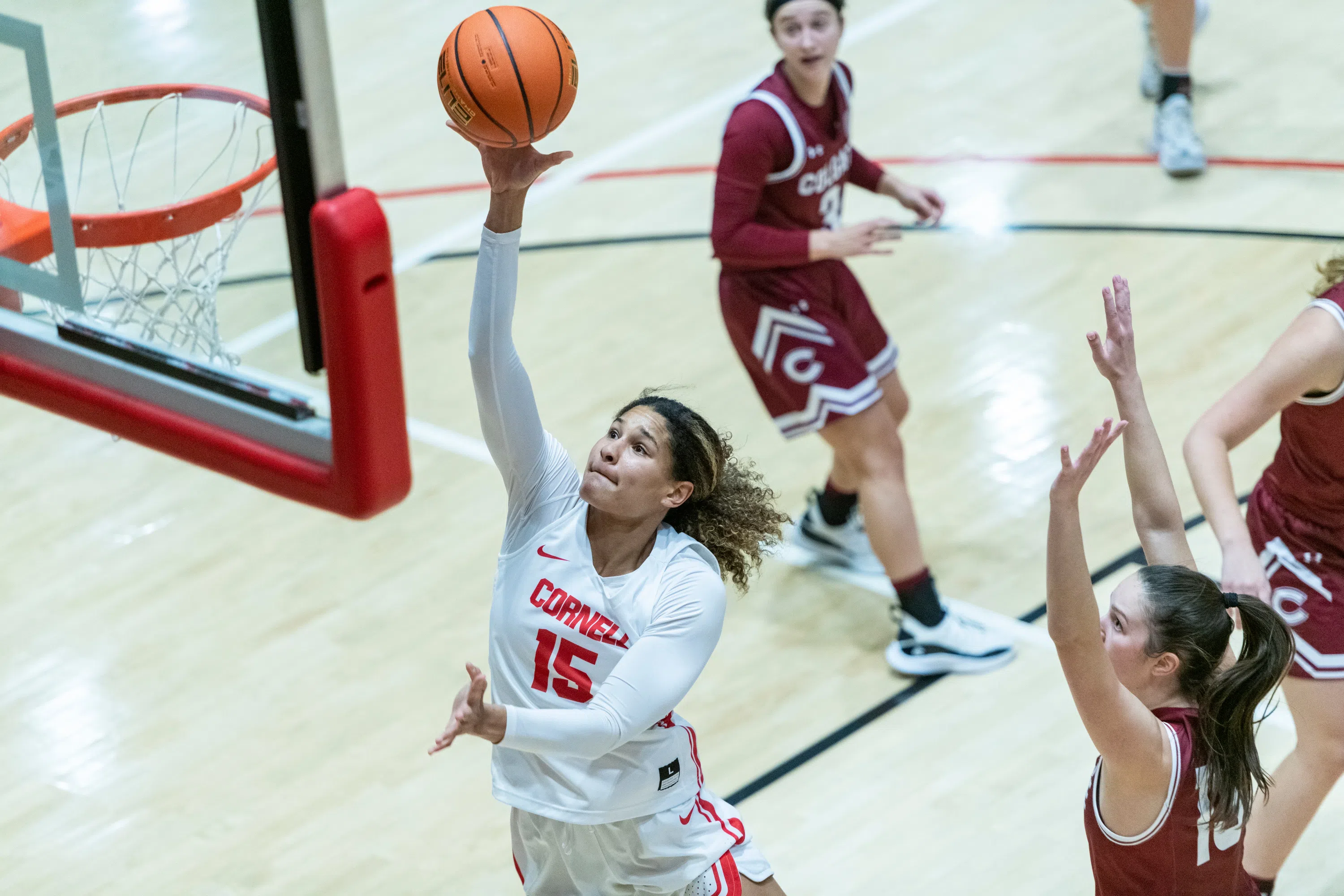 A Cornell women’s basketball player jumps up toward the net, basketball in hand.