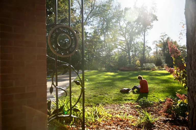 A student studies in the grass in the A.D. White Garden at Cornell University.