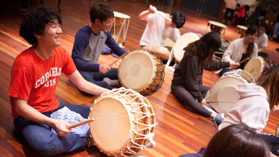 Its members sitting on the floor, a Korean drumming troupe practices in Lincoln Hall, home to the Department of Music.