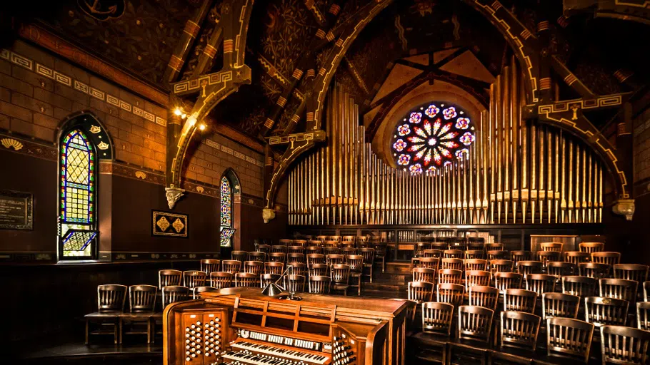 The Aeolian-Skinner organ in Sage Chapel, with a stained glass window in the background.