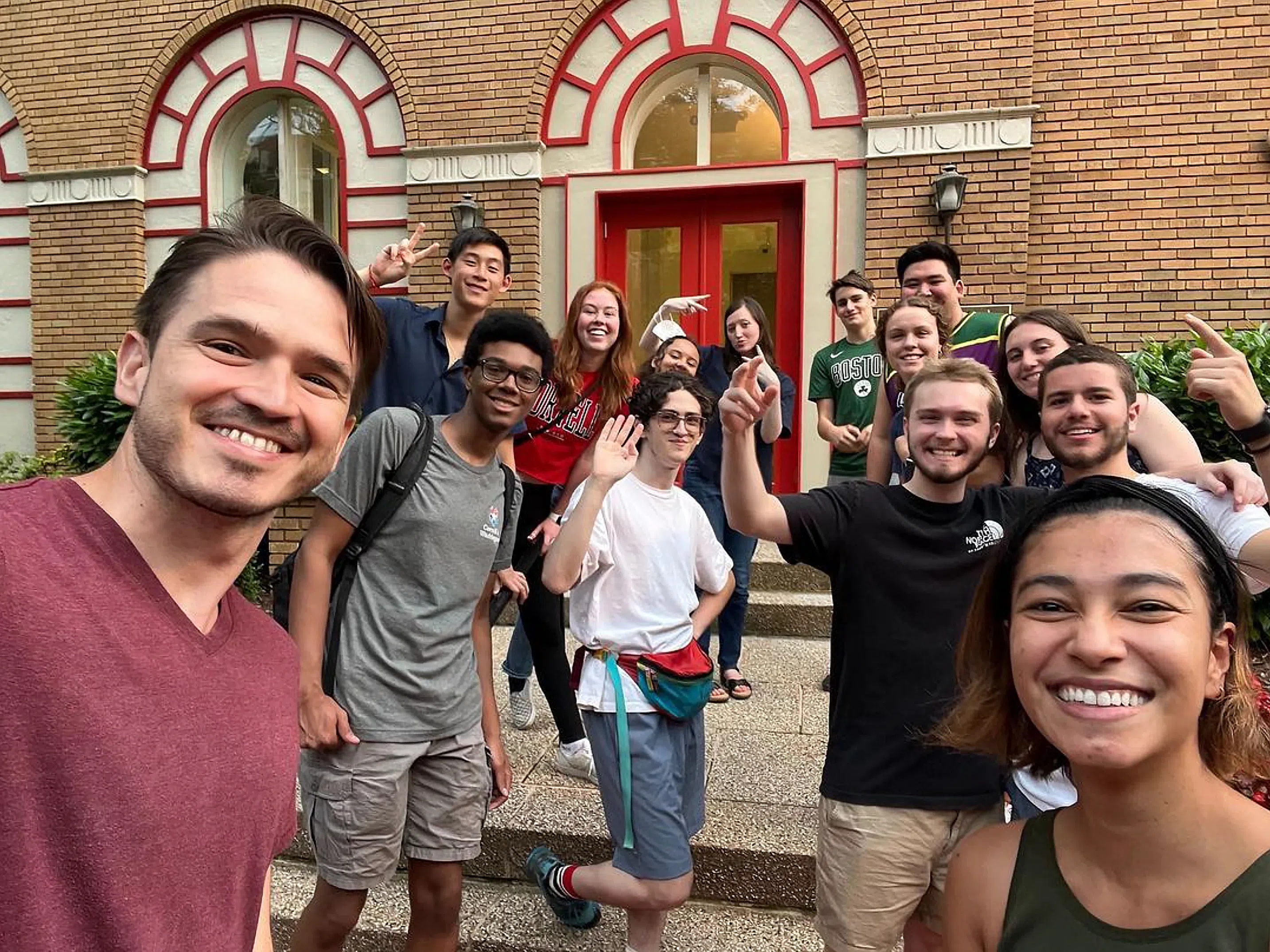 A large group of college students stands in front of a brown brick building in Washington, D.C.