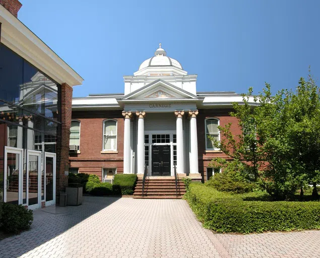 Front view of a two-story, brick building with an four-columned, white entrance and topped with an ornate, domed cupola.