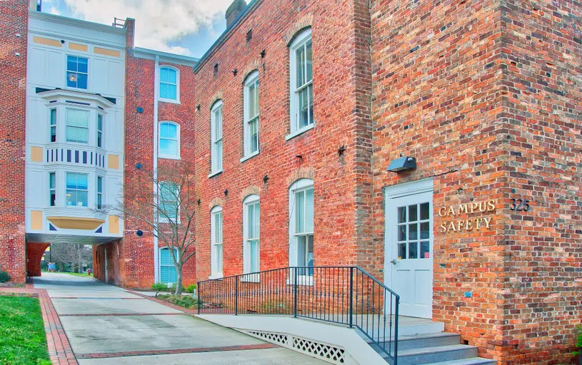 Red brick building with white door and six windows. The words "Campus Safety" appear in gold above the door.