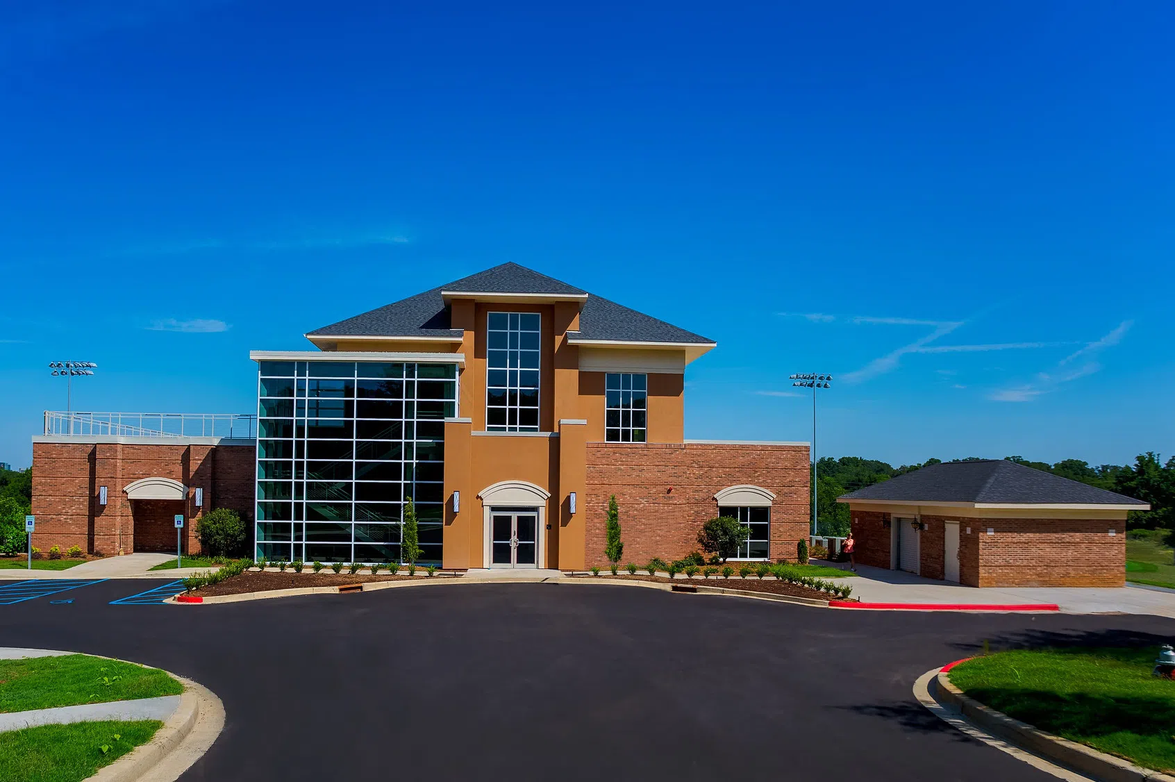 Three story glass and brick building with large asphalt circle in front.