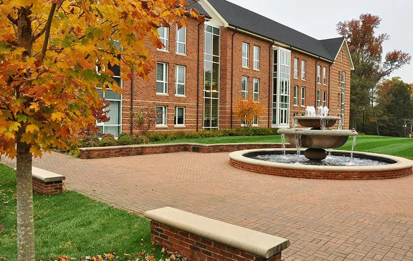 Three story brick building with fountain in the foreground.