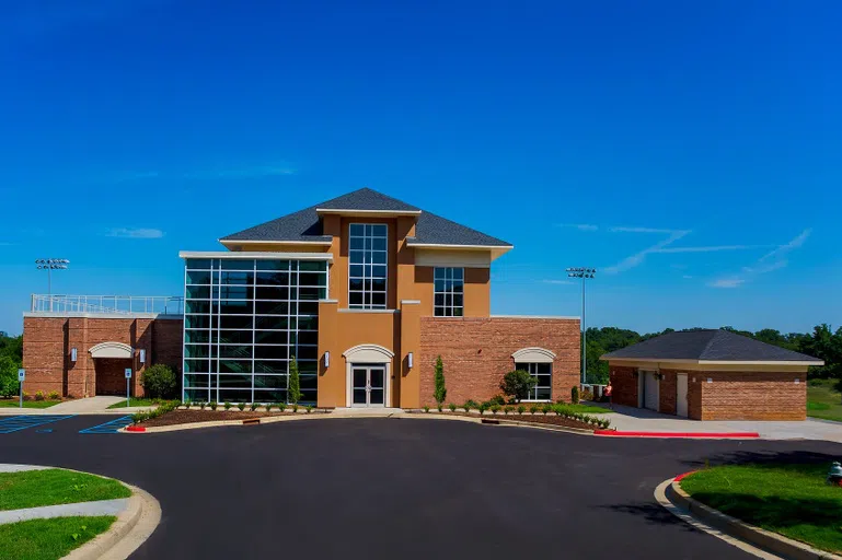 Three story glass and brick building with large asphalt circle in front.