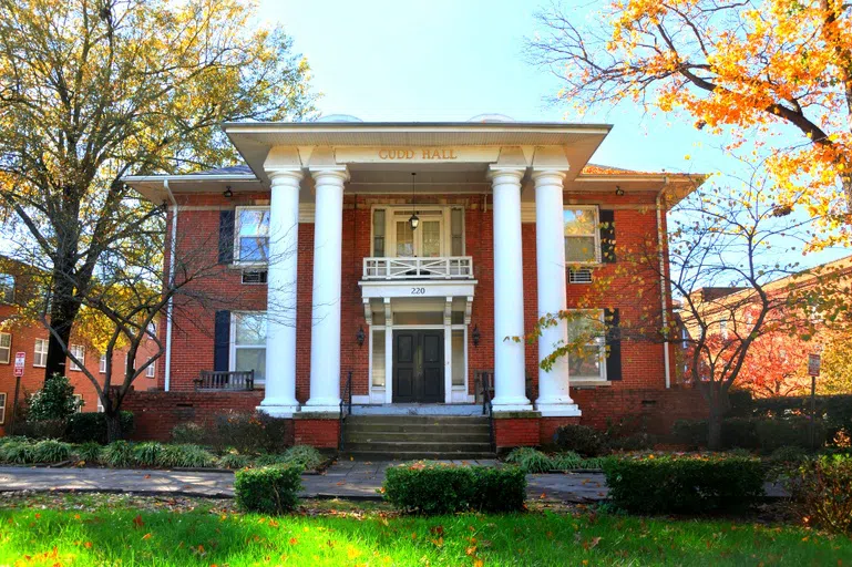 Main entrance to three-story Cudd Hall. White pillars support two patios on the brick building.