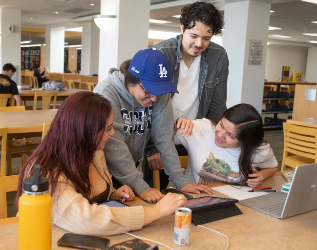 A group of four students studying at a library table