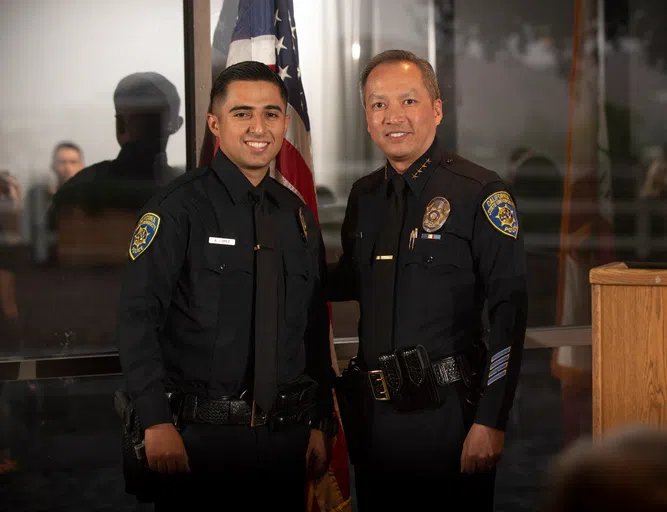 Two police officers stand next to each other smiling