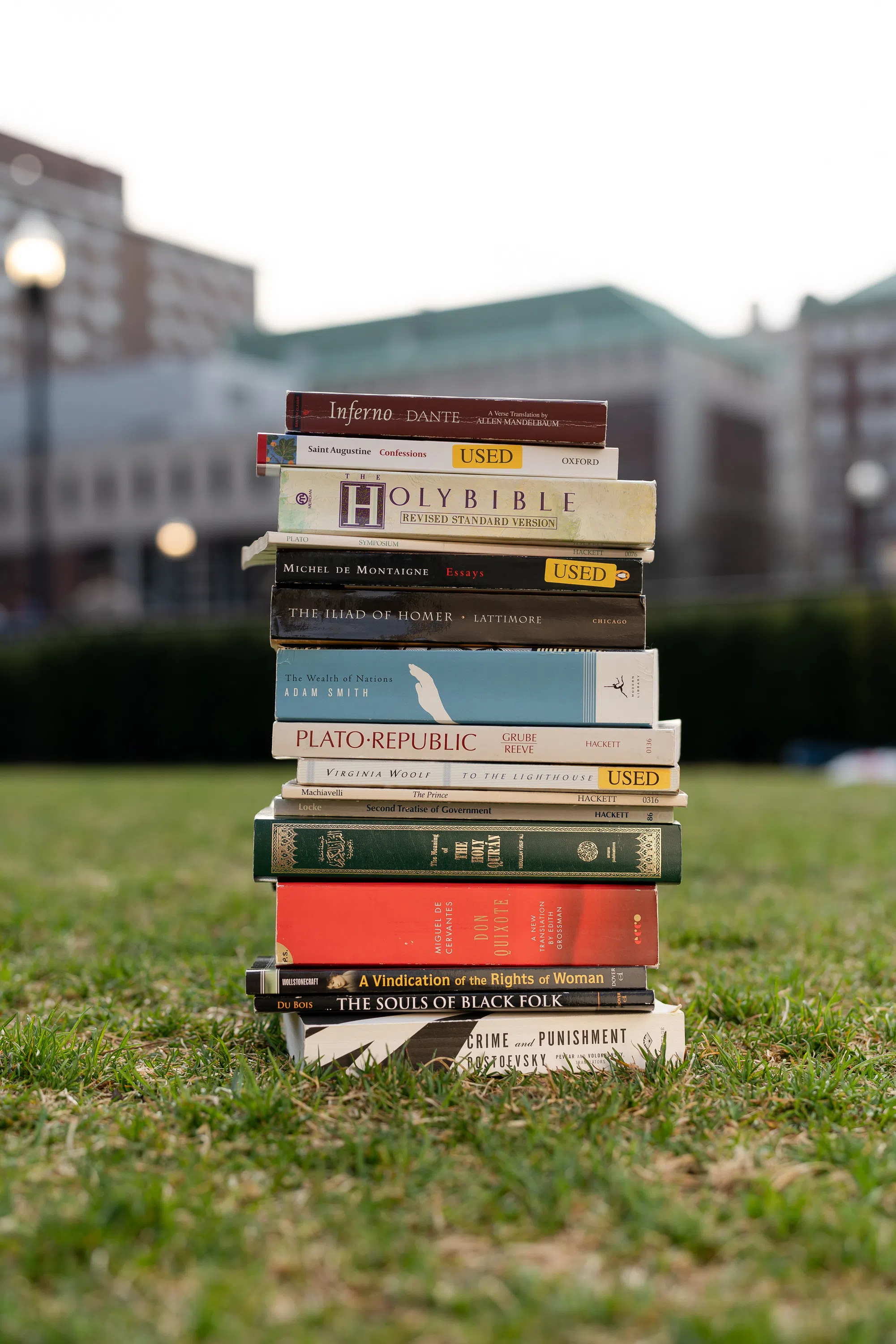 A vertical stack of books sit on a grass lawn.