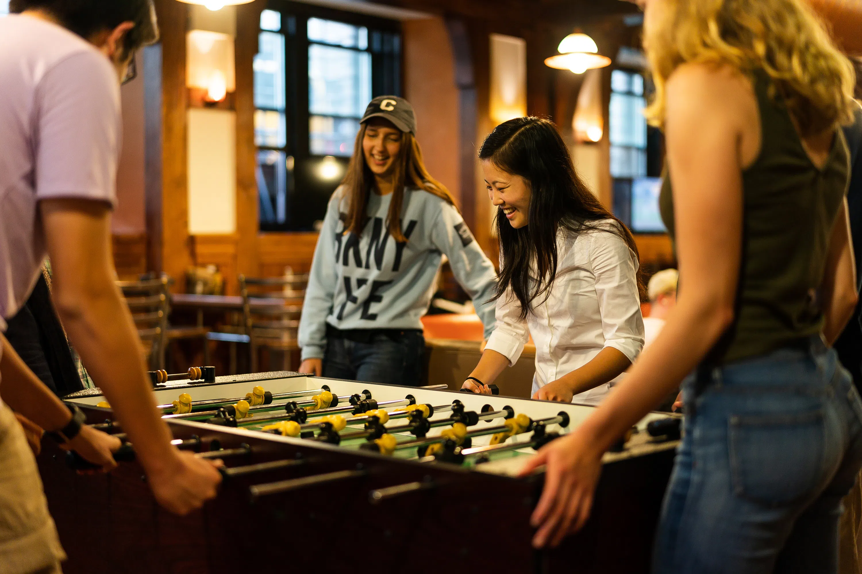 4 students play foosball in an on-campus dining hall