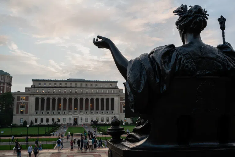 Back of bronze Alma Mater statue with Butler Library in the background.