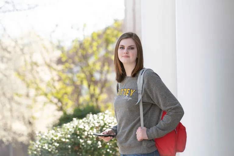 A Cottey student standing in between the large pillars in front of the library