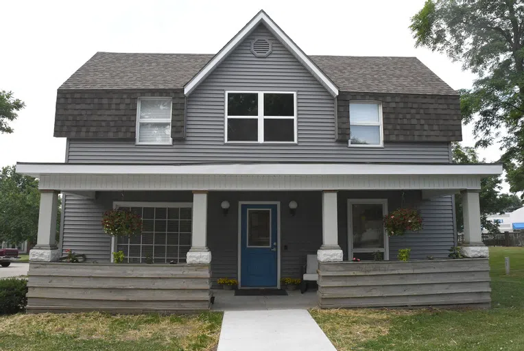 Gray paint, white trim, and a blue door make this two story house feel like a wonderful place to serve as a Student Wellness Center