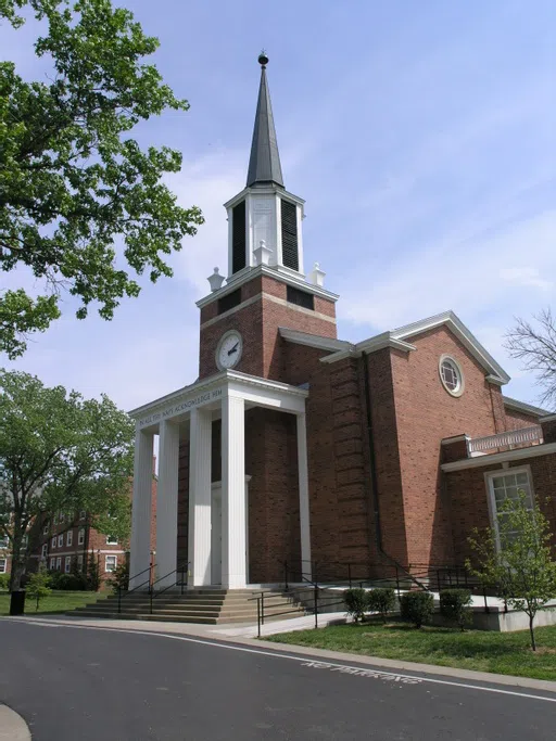 A strong brick chapel with white accents and a tall steeple