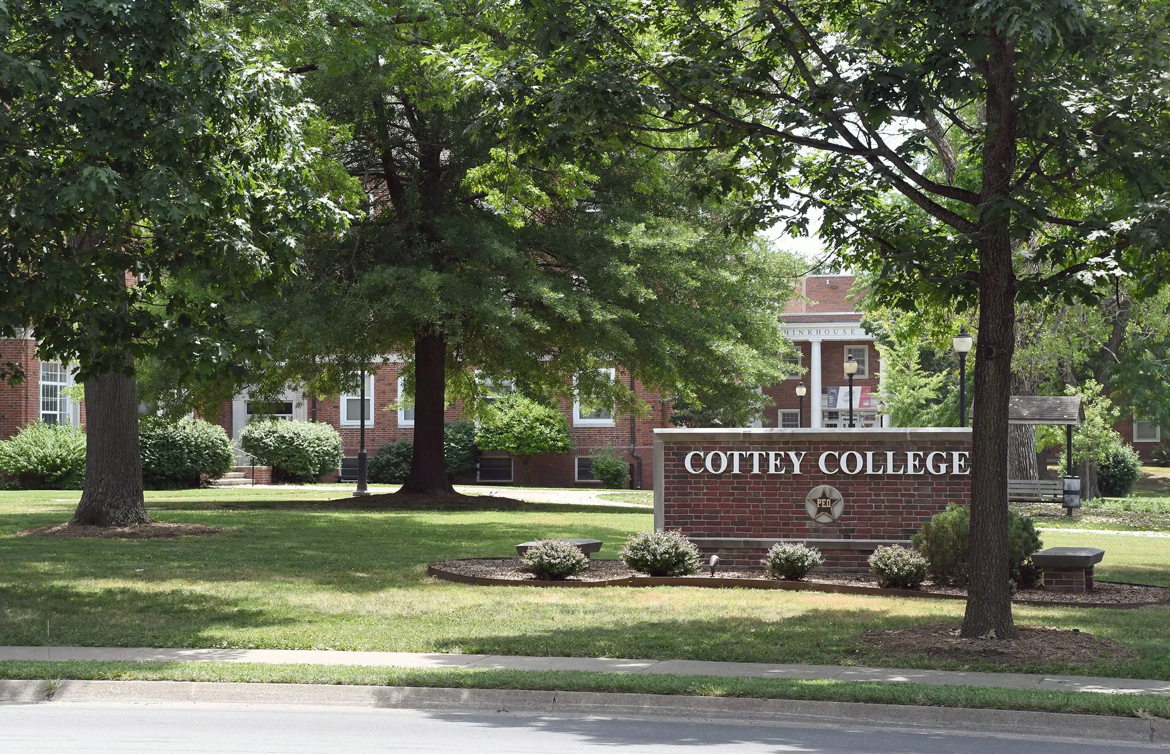 A brick sign that reads, "Cottey College," sits in the middle of a lush campus quad
