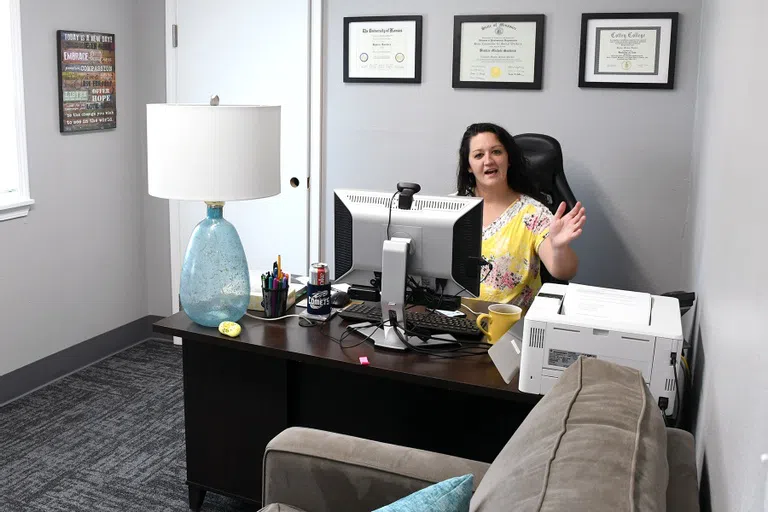 A counseling office inside the Wellness Center with a comfortable couch, soothing gray walls, and a smiling mental health professional 