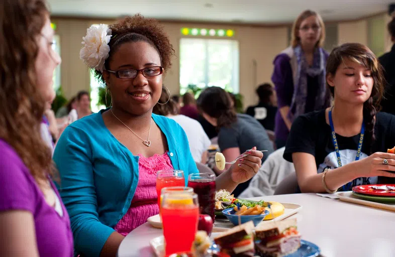 Students sit at a table covered with brightly-colored food