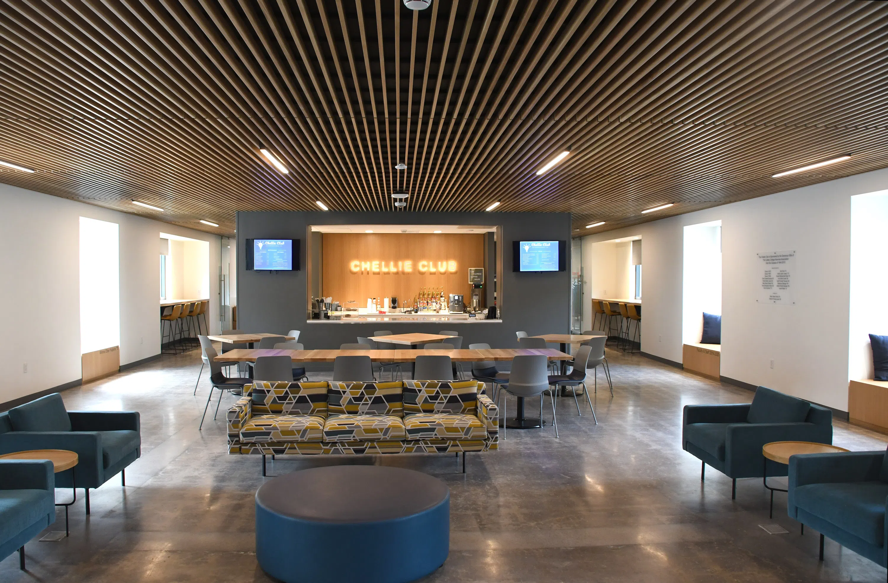 A snack bar, couches, and tables fill a well-light lounge area full of natural light