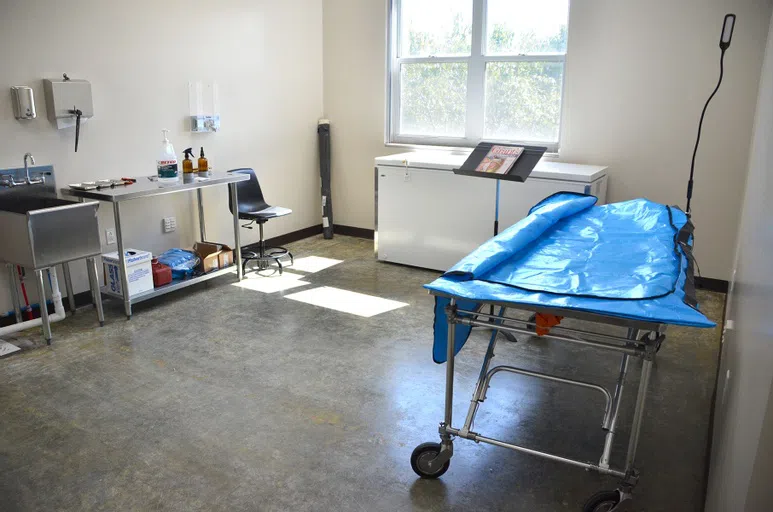 A cadaver lab with table, equipment, and sink