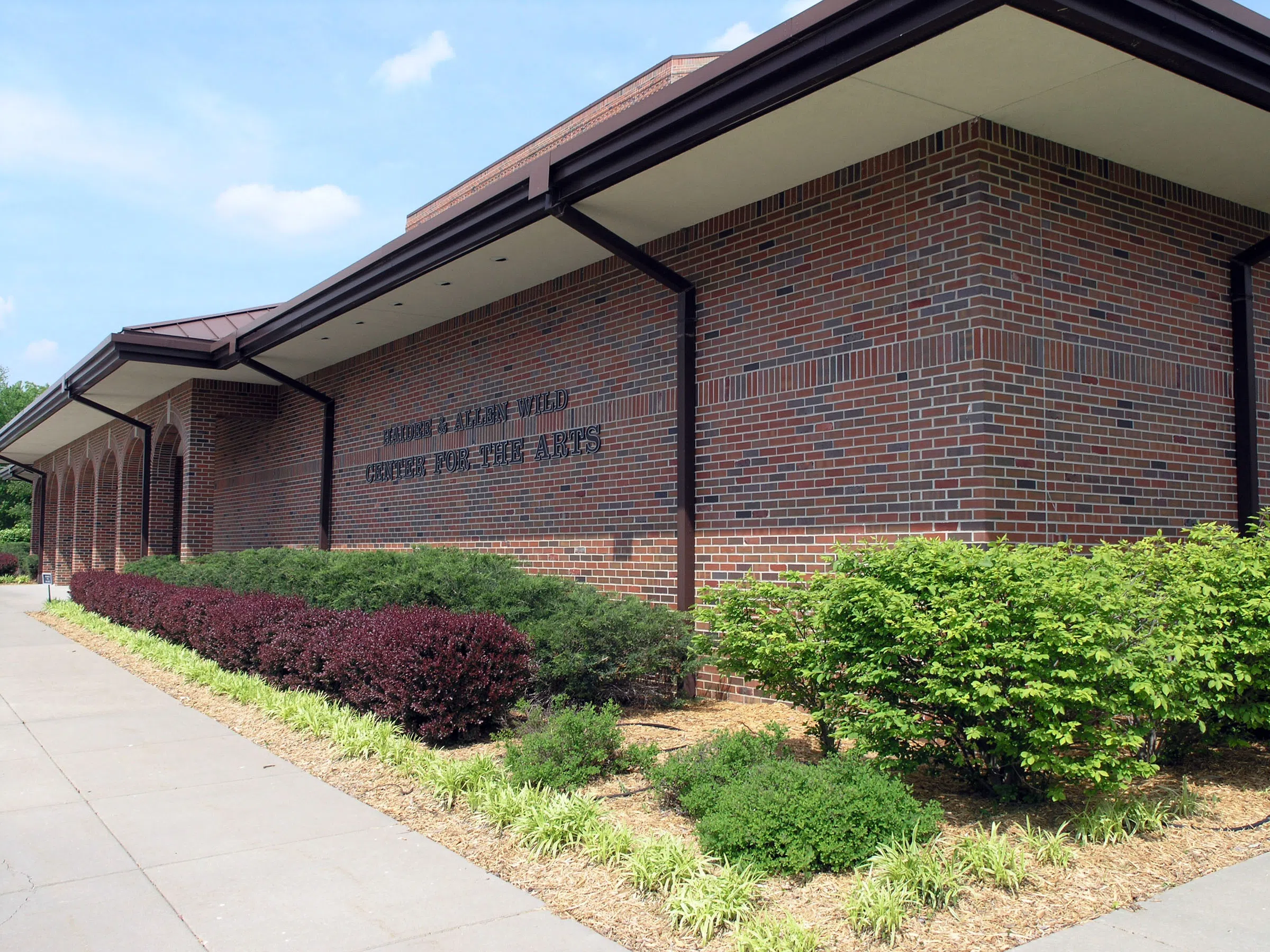 A red, brick building with neatly manicured shrubs lining it's perimeter