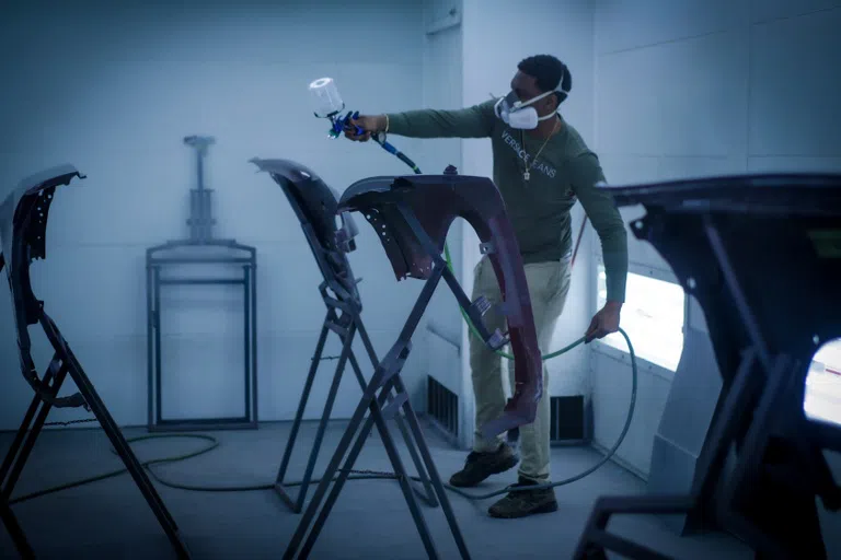 person spray painting a piece of a car