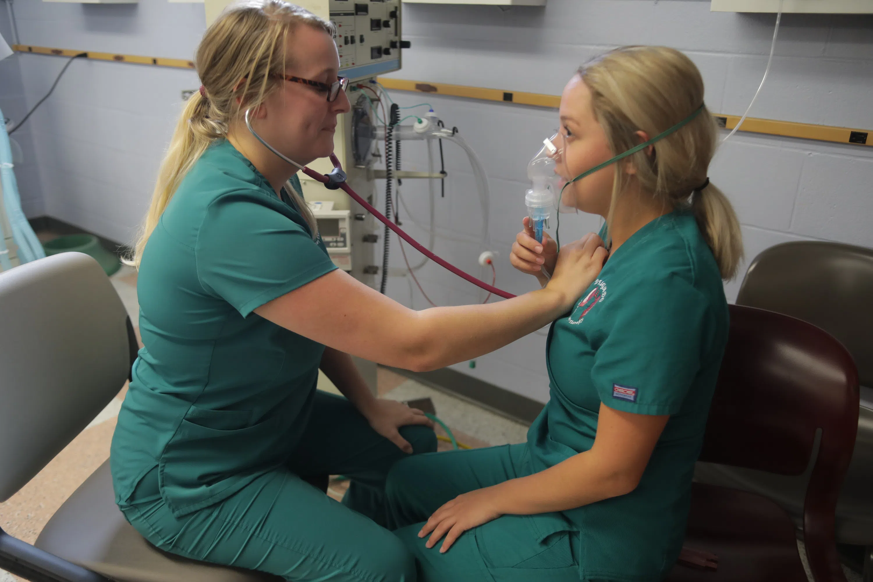 person in scrubs checking another persons heartbeat