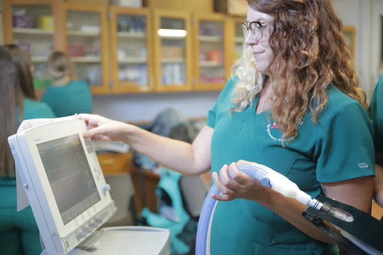 person in scrubs reading something on a respiratory machine