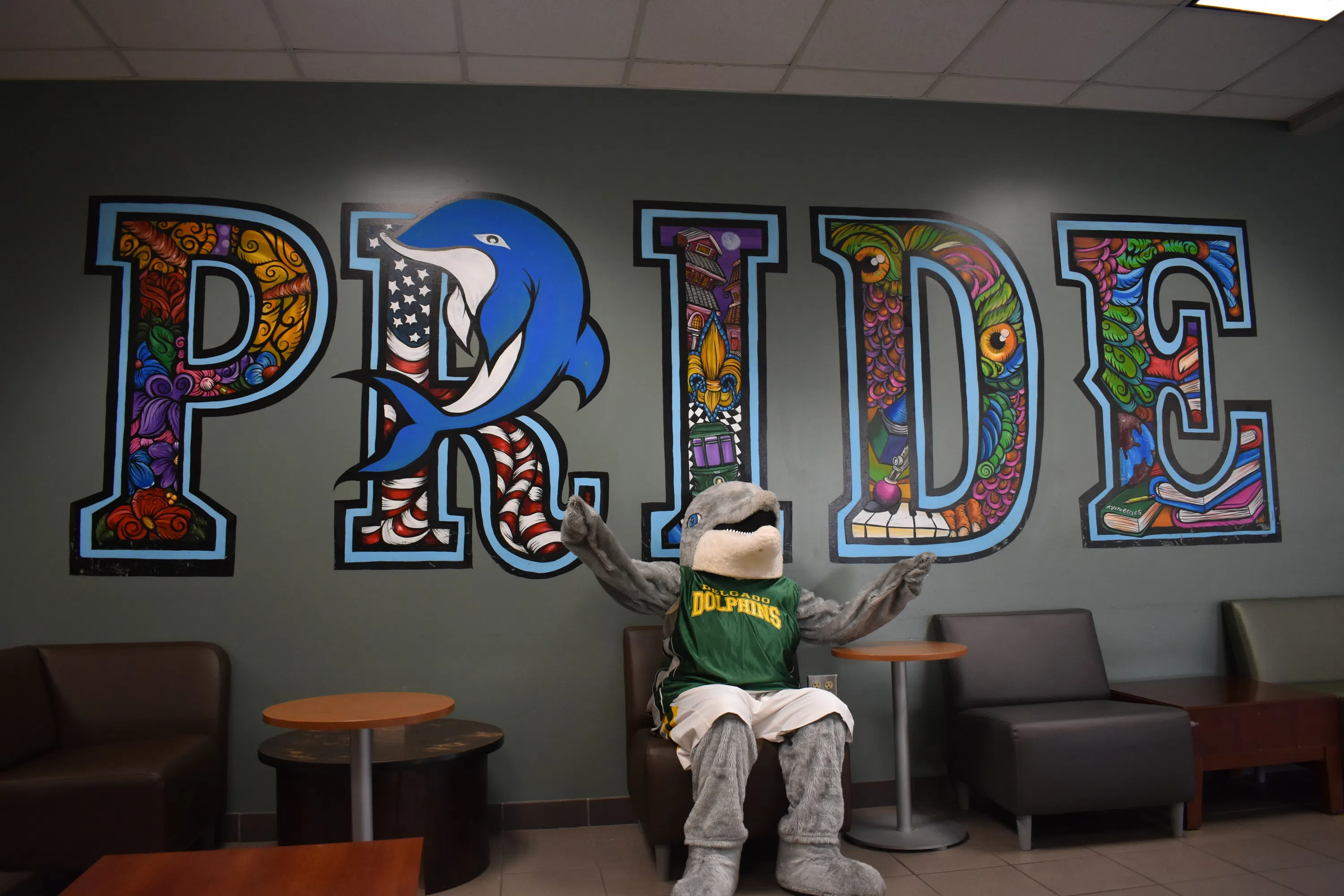 Delgado dolphin mascot i front of Pride mural