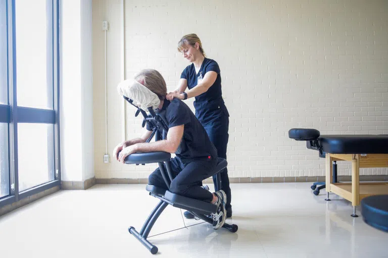 person sitting in massage chair getting a shoulder massage