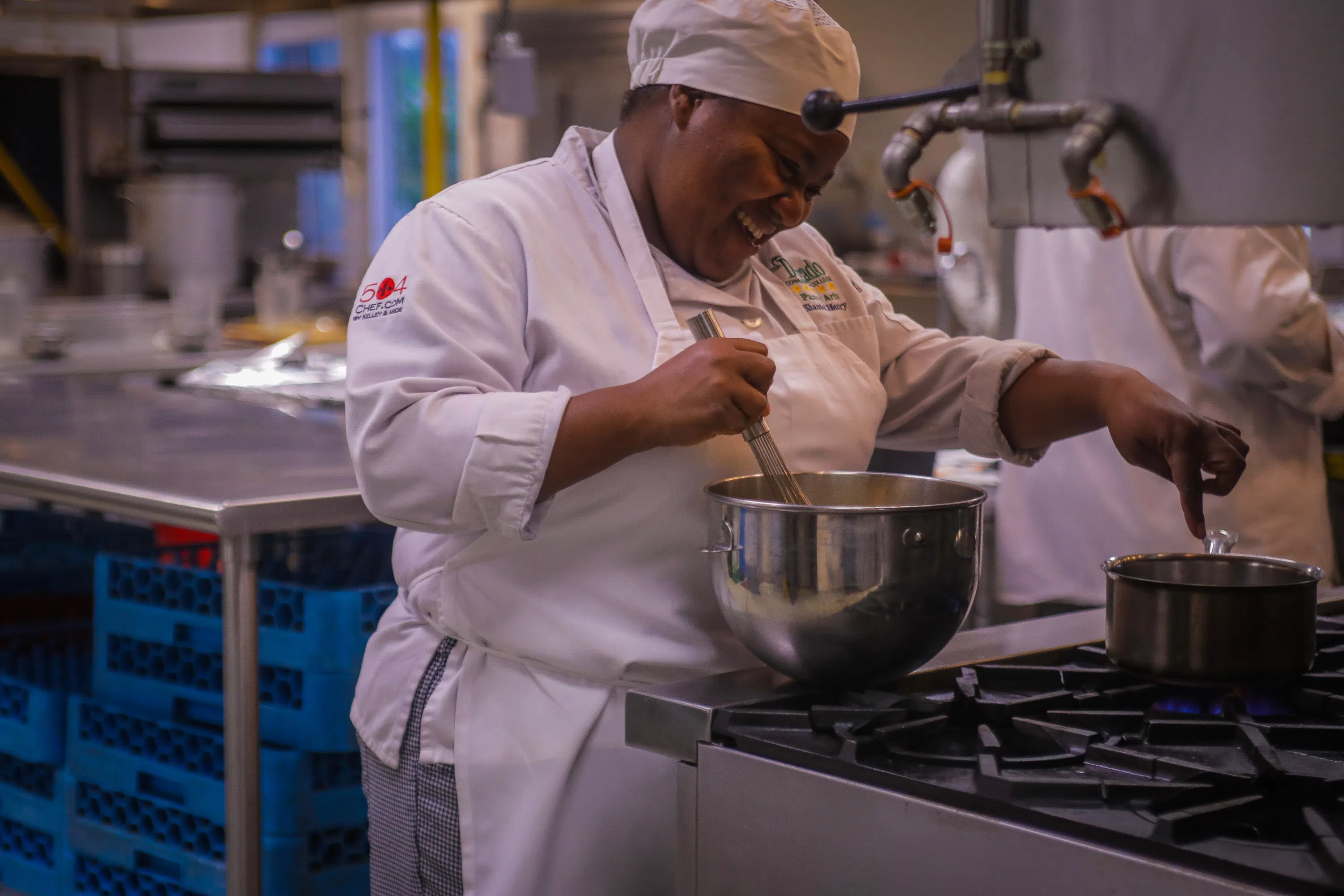 culinary student in chef clothing cooking on stove top