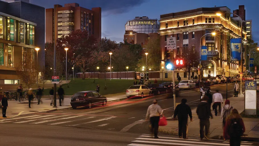 Students walking up 33rd Street toward the Rush Building in the evening.