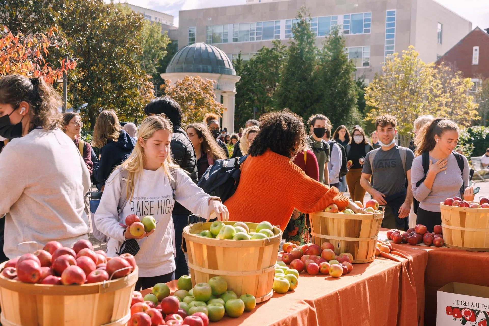 Students grabbing apples at tables in Kogan Plaza
