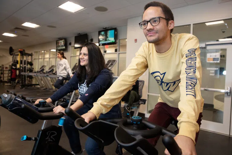 Students using exercise bikes in the West Hall gym