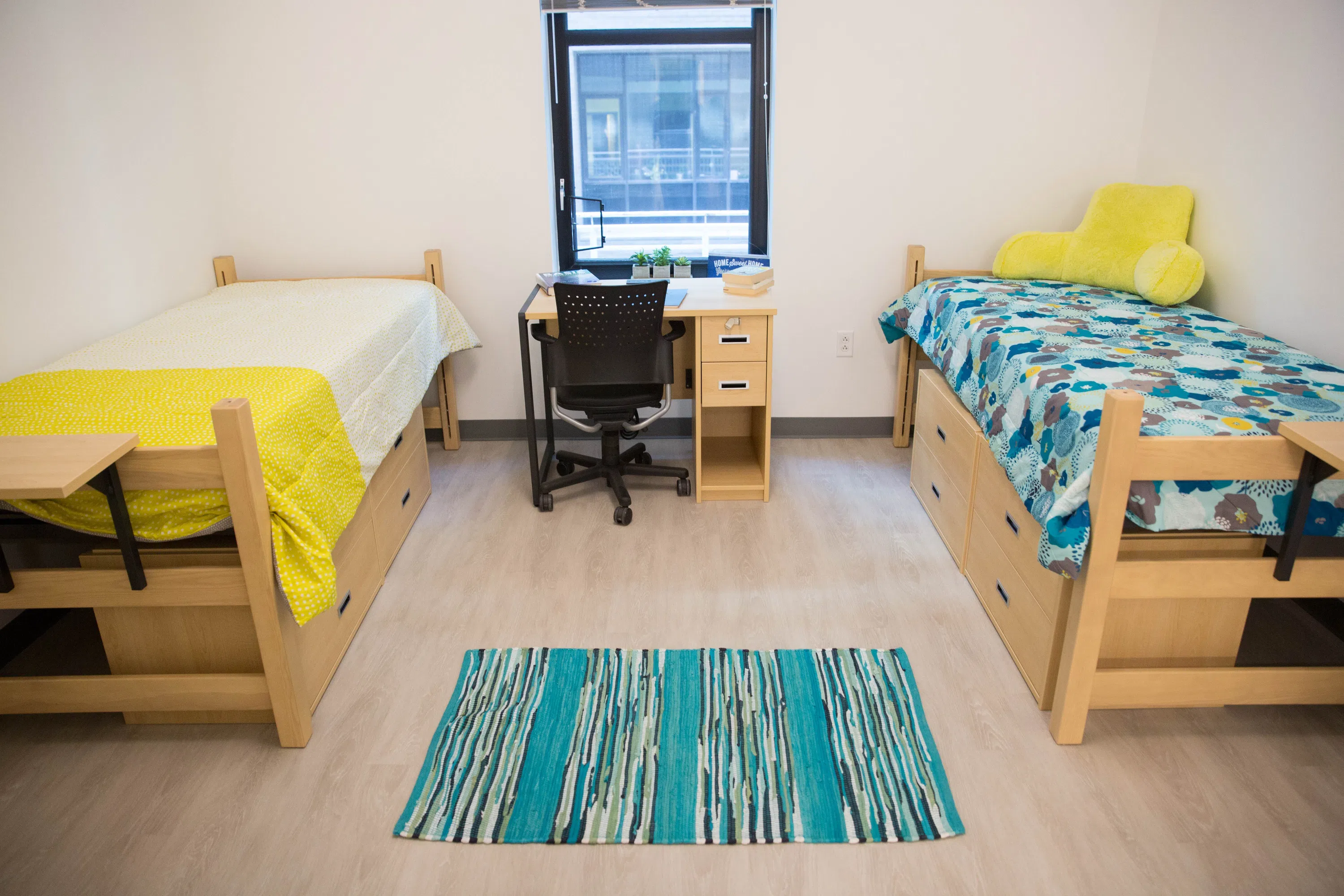 Dorm room with two twin beds, desk, chair and a window. 