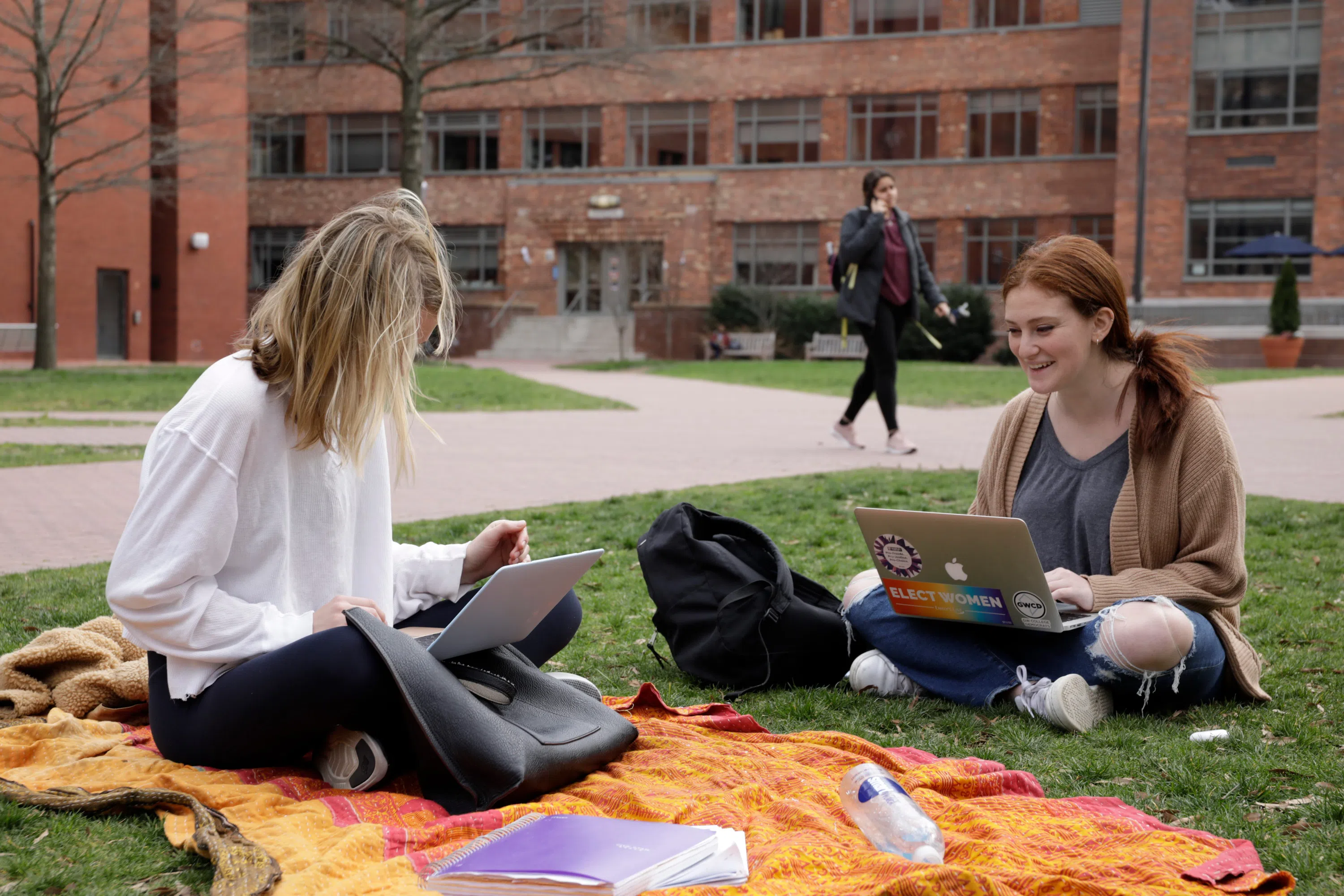 Two students working on laptops on a blanket in U-Yard