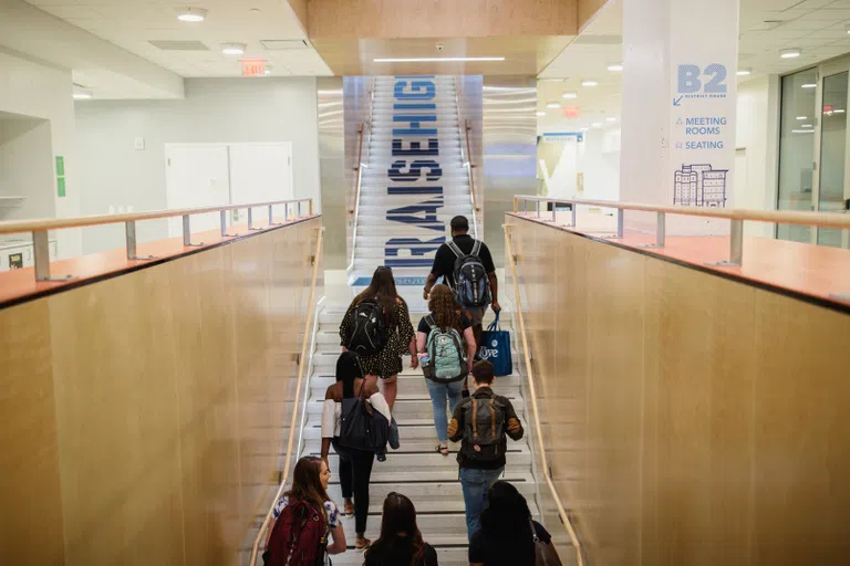 Students walking up a staircase inside District House. 