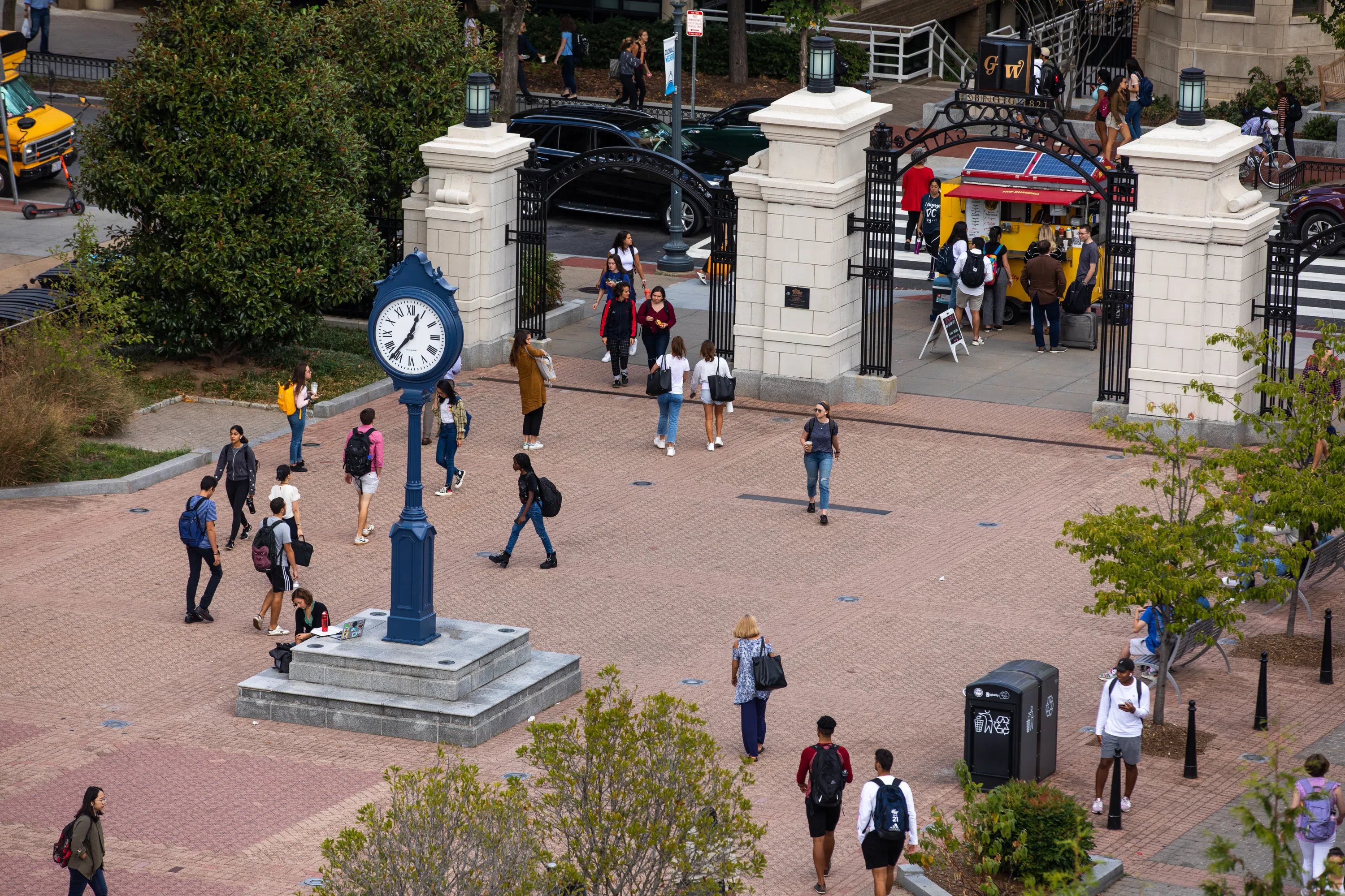 Students walking in Kogan Plaza near a clock tower.