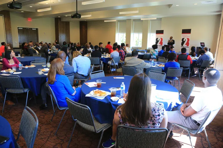 People at round tables listen to a lecturer in the ballroom